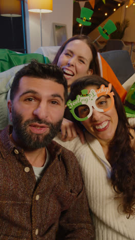Vertical-Video-POV-Shot-Of-Friends-Dressing-Up-At-Home-Celebrating-At-St-Patrick's-Day-Party-Making-Video-Call-On-Mobile-Phone